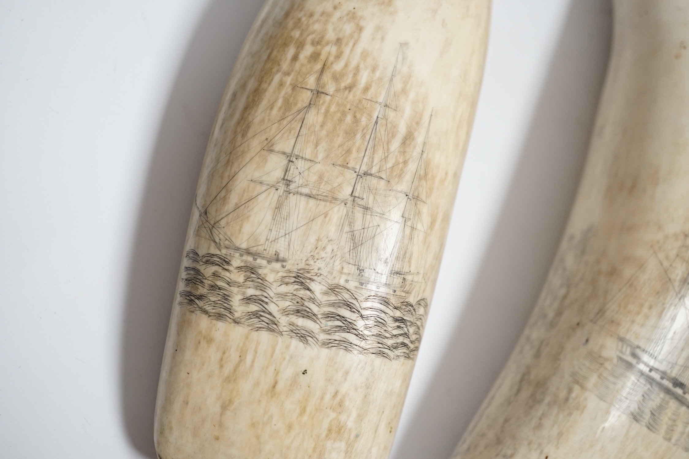 Two 19th century scrimshaw sperm whale teeth, each incised with a ship, 20cm in length